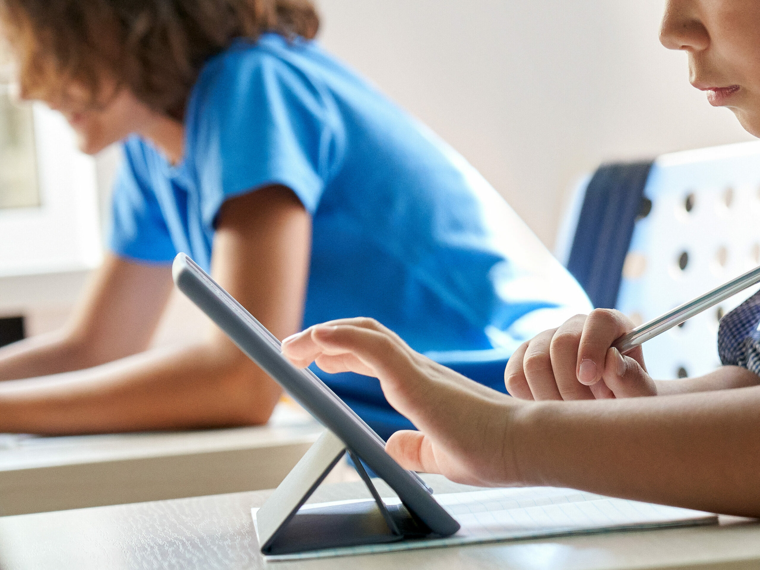 Children sitting at desks on tablets. 